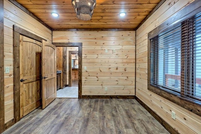 spare room with wood walls, wood ceiling, and dark hardwood / wood-style flooring