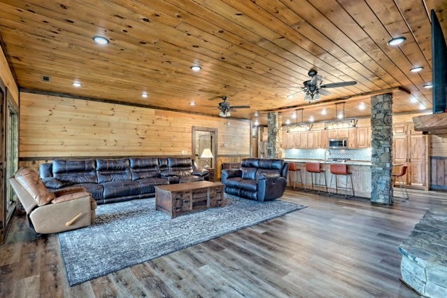 living room featuring wooden walls, ceiling fan, wood ceiling, and dark hardwood / wood-style flooring