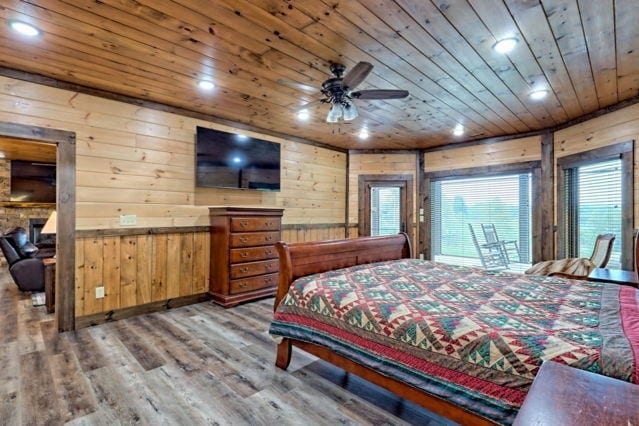 bedroom with ceiling fan, wood walls, wooden ceiling, and wood-type flooring