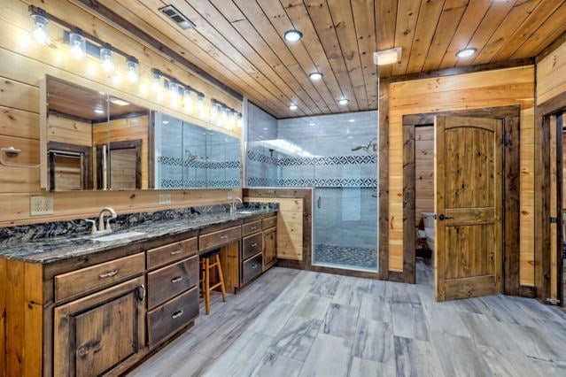 bathroom featuring vanity, wooden walls, a shower with shower door, and hardwood / wood-style flooring