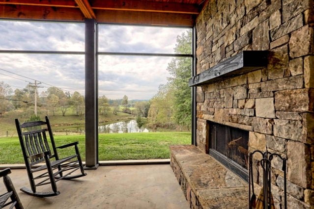 sunroom / solarium with a water view and an outdoor stone fireplace