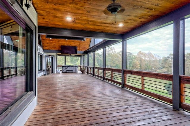 unfurnished sunroom featuring ceiling fan, a wealth of natural light, and wooden ceiling