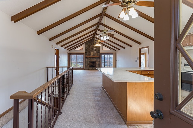 kitchen featuring beamed ceiling, light carpet, ceiling fan, and a fireplace