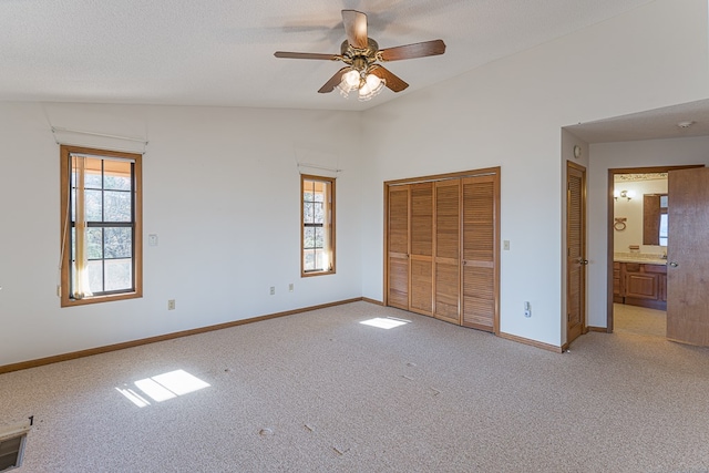 unfurnished bedroom with ceiling fan, lofted ceiling, light carpet, and connected bathroom