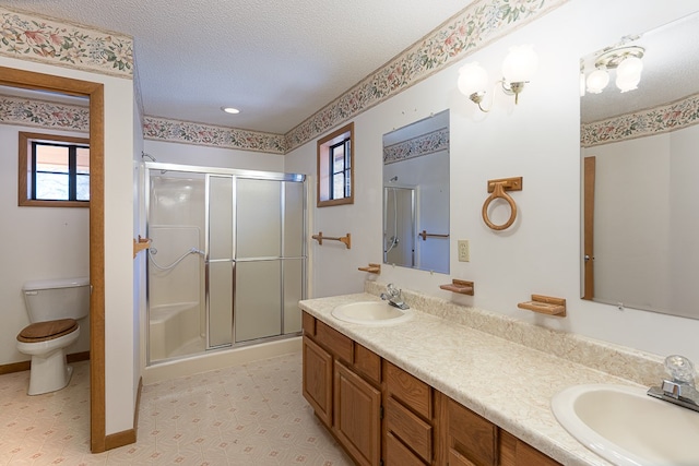 bathroom featuring a textured ceiling, vanity, toilet, and walk in shower