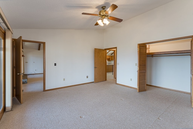 unfurnished bedroom with a textured ceiling, light colored carpet, vaulted ceiling, ceiling fan, and a closet