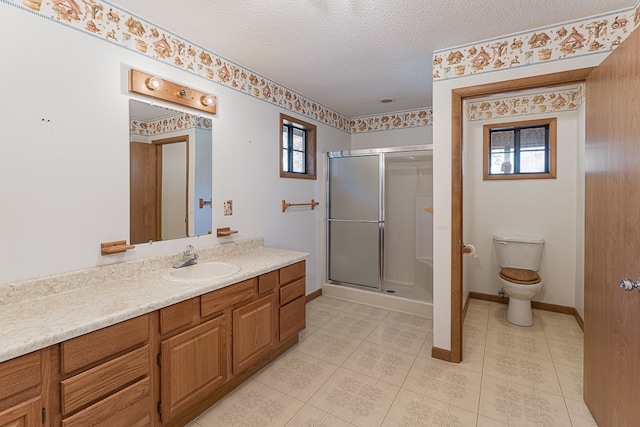 bathroom featuring toilet, vanity, a textured ceiling, and walk in shower