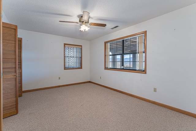 unfurnished room featuring ceiling fan, a textured ceiling, and light carpet