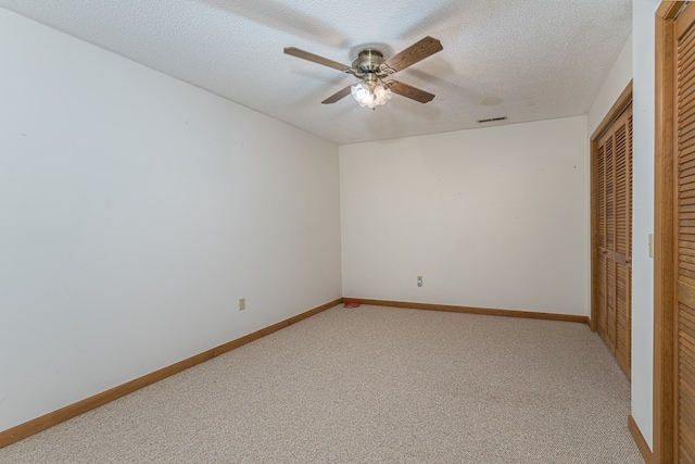 unfurnished bedroom featuring ceiling fan, light carpet, and a textured ceiling