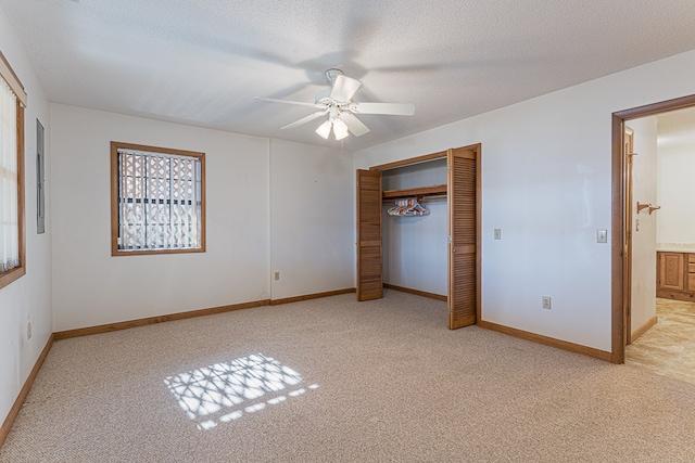 unfurnished bedroom with a textured ceiling, a closet, ceiling fan, and light colored carpet