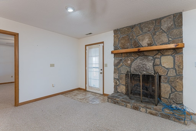 unfurnished living room with carpet flooring, a stone fireplace, and a textured ceiling