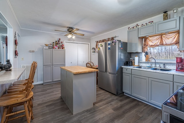 kitchen with freestanding refrigerator, gray cabinetry, a sink, and ornamental molding