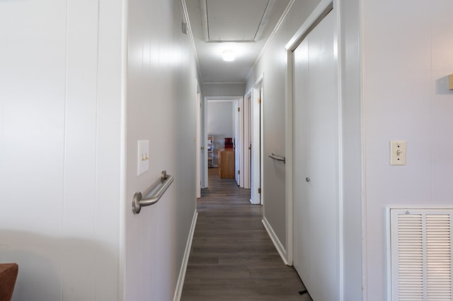 hall with attic access, dark wood-style flooring, baseboards, and crown molding