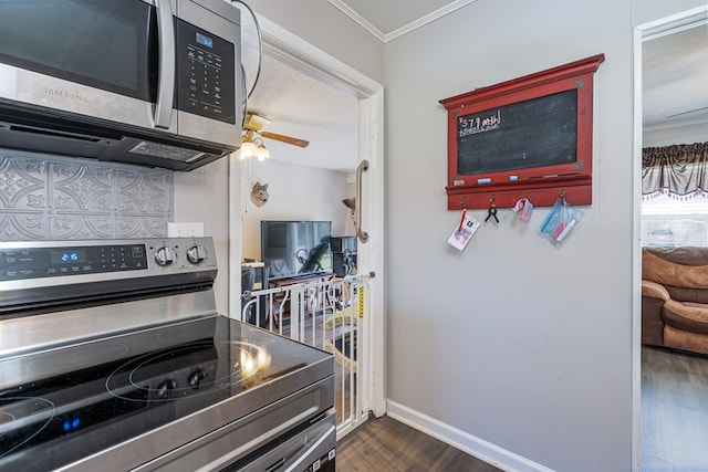 kitchen with stainless steel appliances, dark wood finished floors, ornamental molding, baseboards, and a ceiling fan