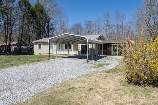 view of front of property featuring gravel driveway, a sunroom, a front yard, a carport, and crawl space