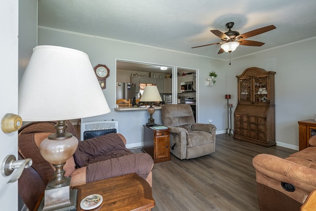 living room with ceiling fan, wood finished floors, baseboards, heating unit, and crown molding