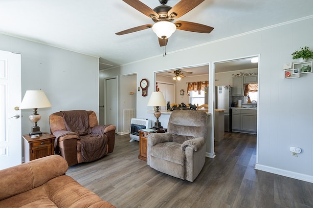 living area featuring a ceiling fan, dark wood-style flooring, heating unit, and crown molding