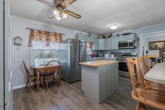 kitchen with stainless steel appliances, wood counters, ornamental molding, a ceiling fan, and dark wood finished floors