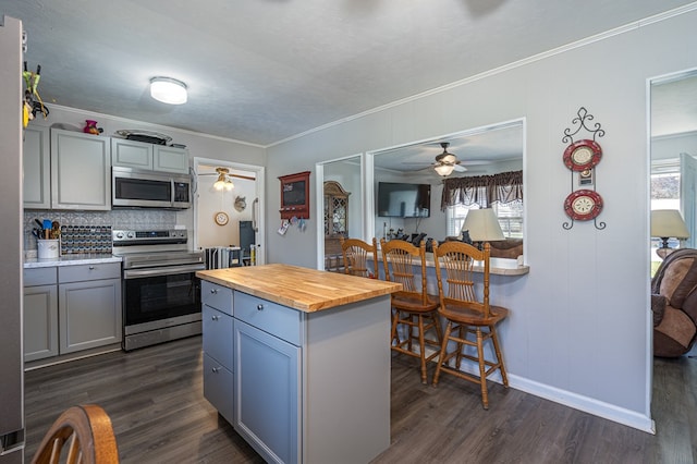kitchen with appliances with stainless steel finishes, wood counters, gray cabinets, dark wood-type flooring, and crown molding