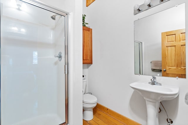 bathroom featuring a shower with door, hardwood / wood-style flooring, sink, and toilet