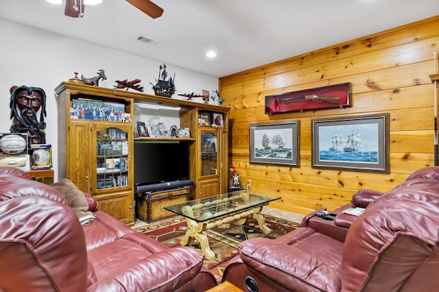 living room featuring ceiling fan and wood walls