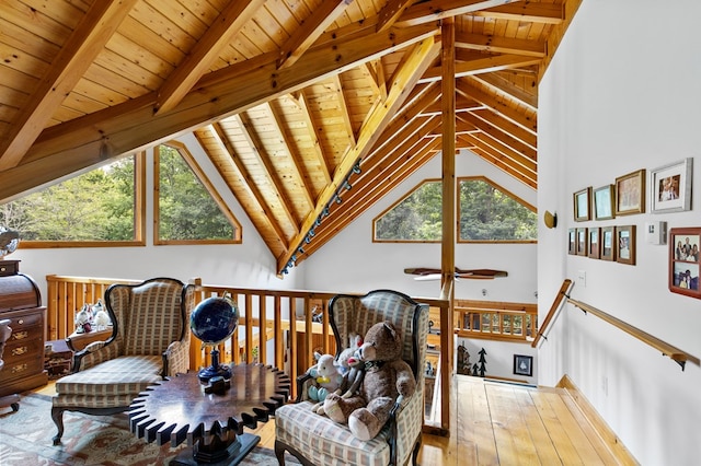 living area featuring beamed ceiling, wood ceiling, plenty of natural light, and hardwood / wood-style flooring