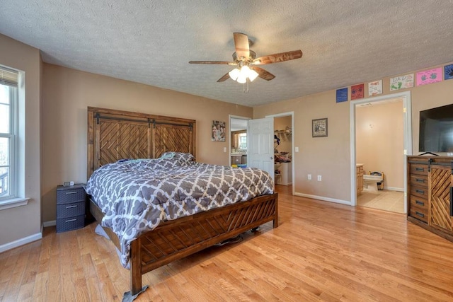 bedroom featuring connected bathroom, a textured ceiling, light hardwood / wood-style floors, and ceiling fan