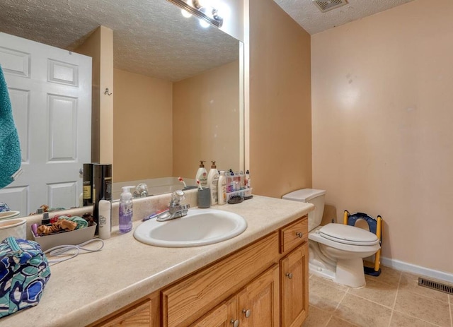 bathroom with vanity, toilet, tile patterned flooring, and a textured ceiling