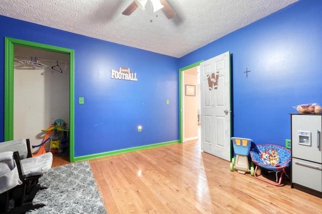 playroom featuring ceiling fan, hardwood / wood-style flooring, and a textured ceiling