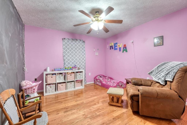 interior space with ceiling fan, a textured ceiling, and light wood-type flooring