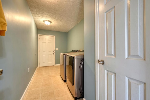 laundry area with washing machine and dryer and a textured ceiling