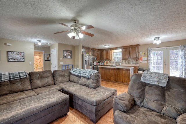 living room featuring a textured ceiling, light hardwood / wood-style floors, and french doors