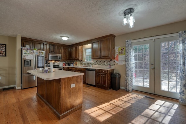 kitchen featuring french doors, appliances with stainless steel finishes, a kitchen island, and light hardwood / wood-style flooring