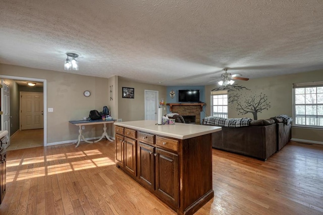 kitchen featuring ceiling fan, light hardwood / wood-style flooring, a center island, and a textured ceiling