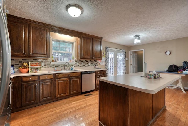 kitchen with french doors, sink, stainless steel appliances, light hardwood / wood-style floors, and backsplash