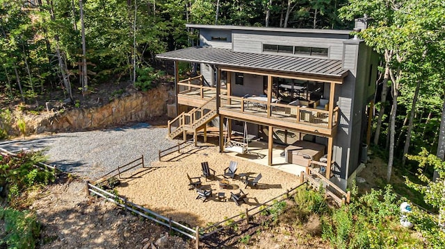 rear view of house with a patio, an outdoor fire pit, stairway, a standing seam roof, and a chimney