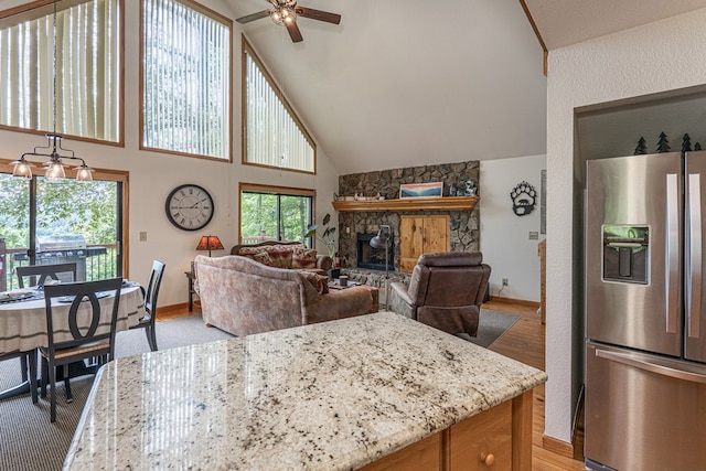 40 White Cloud Dr, Murphy, NC 28906 - kitchen with stainless steel fridge, ceiling fan, a fireplace, light stone countertops, and high vaulted ceiling