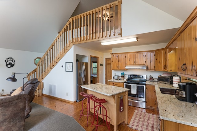 40 White Cloud Dr, Murphy, NC 28906 - kitchen with appliances with stainless steel finishes, under cabinet range hood, light wood-type flooring, a kitchen island, and a kitchen breakfast bar