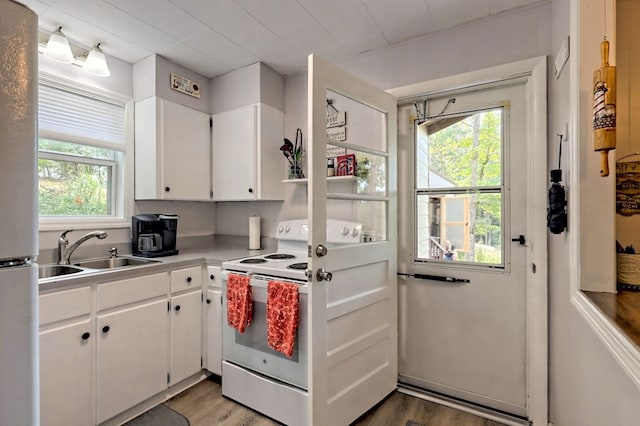 kitchen with sink, white appliances, wood-type flooring, and white cabinets