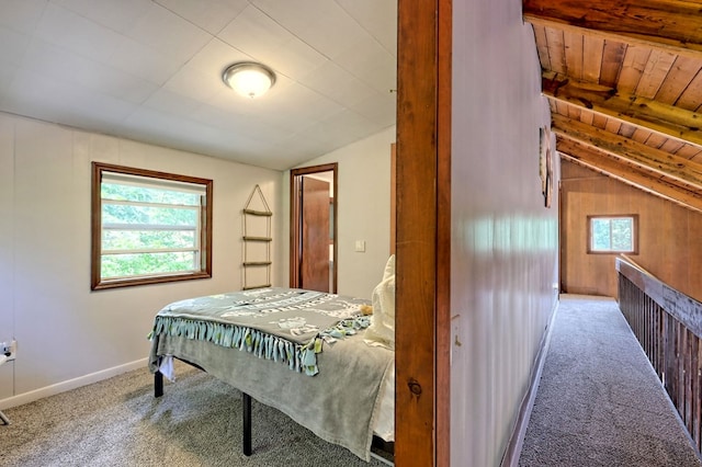 carpeted bedroom featuring multiple windows, vaulted ceiling with beams, wood ceiling, and wood walls