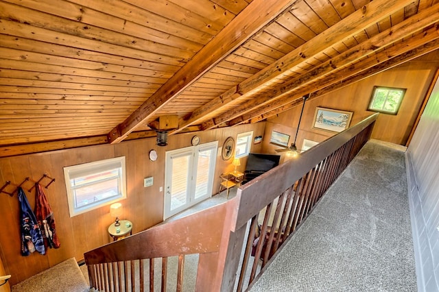 staircase with wood ceiling, carpet flooring, beam ceiling, and wood walls