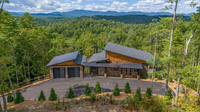 view of front of property with stone siding, a mountain view, and a forest view