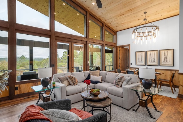 living area with a wealth of natural light, a notable chandelier, wooden ceiling, and wood-type flooring