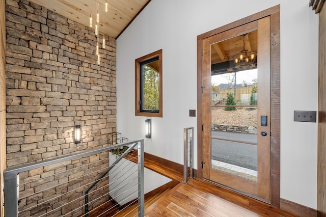 doorway featuring an inviting chandelier, wood ceiling, wood finished floors, and baseboards