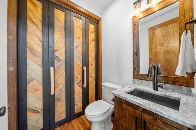 bathroom featuring toilet, vanity, and wood finished floors