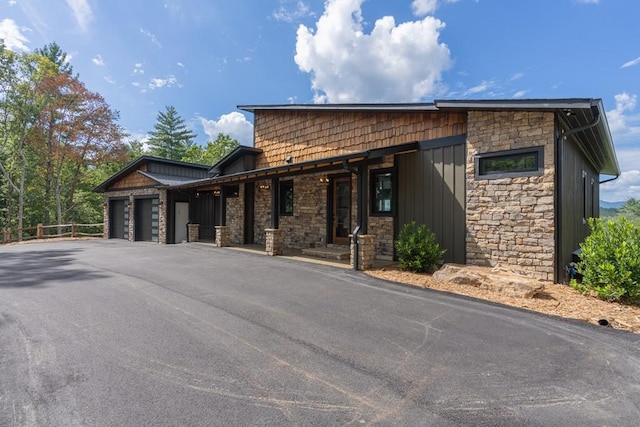 view of front of property featuring driveway, a garage, and stone siding