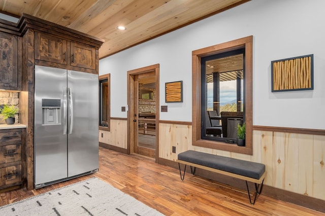 kitchen featuring dark brown cabinets, light wood-type flooring, wainscoting, wooden ceiling, and stainless steel refrigerator with ice dispenser