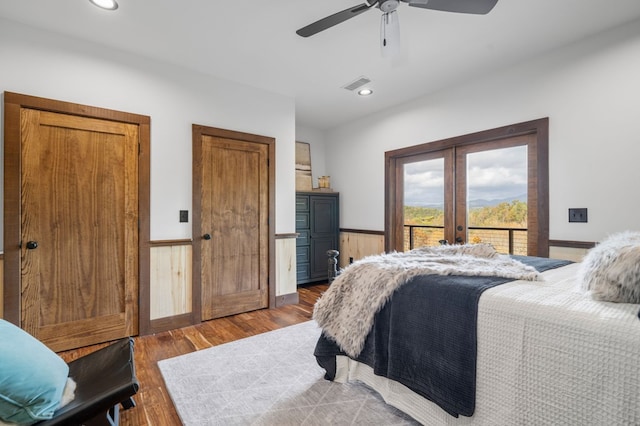 bedroom featuring wood finished floors, visible vents, french doors, wainscoting, and access to outside