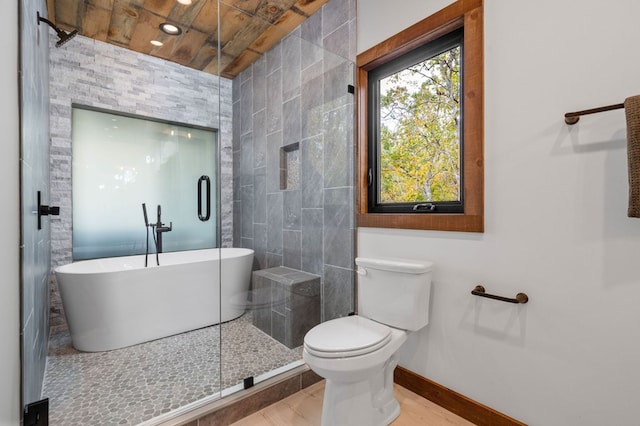 bathroom with a soaking tub, toilet, a shower, and baseboards