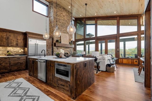 kitchen with dark wood-type flooring, an island with sink, wood ceiling, and appliances with stainless steel finishes